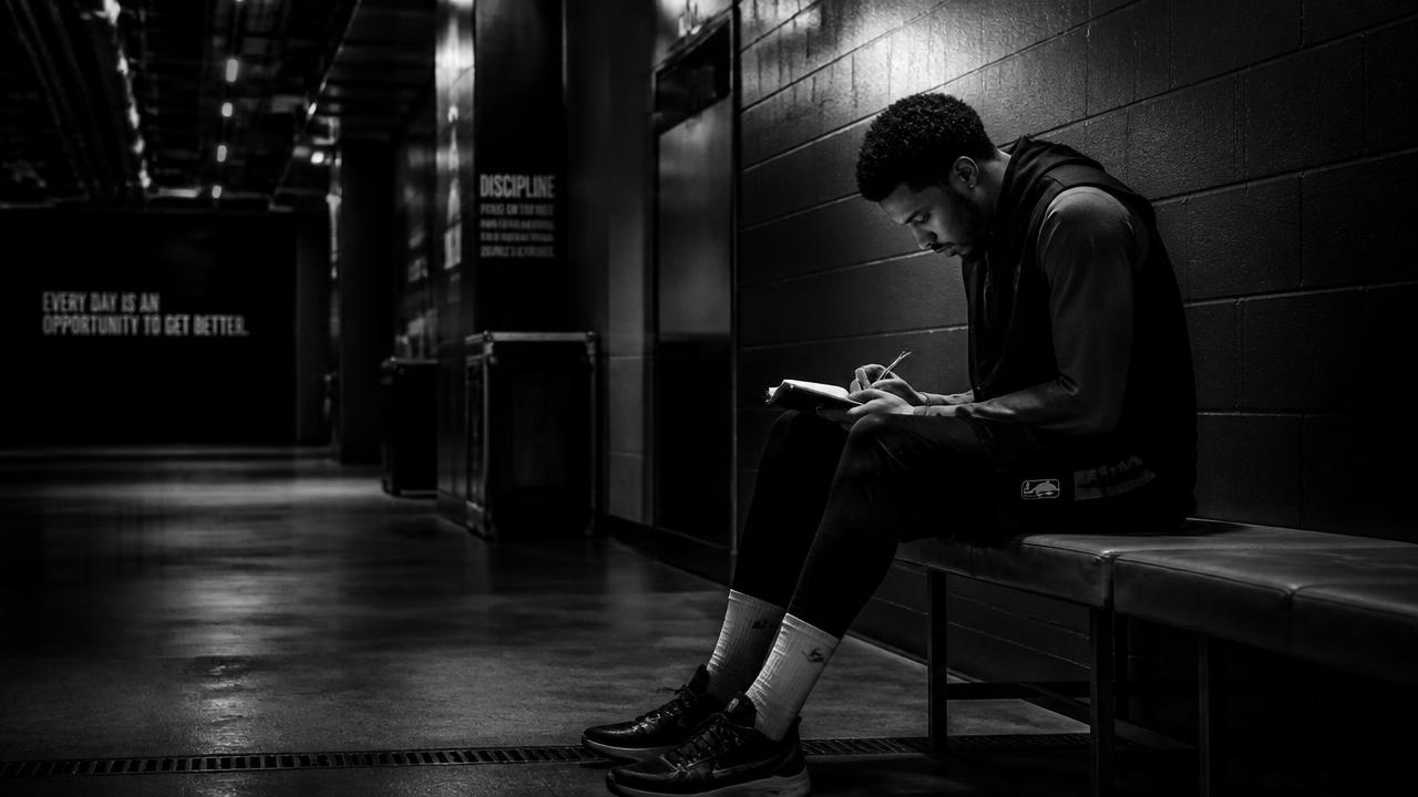 Athlete reflecting with a notebook in a stadium tunnel